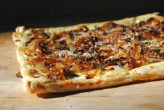 a square pizza sitting on top of a wooden cutting board