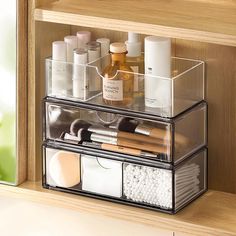 two clear containers holding cosmetics and personal care items in front of a wooden counter top