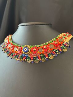 Elevate your style with this Handmade Boho Beaded Necklace featuring an enchanting Evil Eye Charm and a vibrant floral design.  This unique statement piece of ethnic jewelry is perfect for adding a touch of color and culture to any outfit.  Product Details:  * Length: 41-42 cm (16-16.5 inches)  * Materials: Crafted with meticulous attention to detail using seed beads and glass beads Care  Instructions: To ensure the longevity of your beautiful necklace, please avoid contact with water and chemic Bohemian Multicolor Evil Eye Necklace, Multicolor Beaded Amulet Necklaces, Bohemian Flower-shaped Jewelry With Colorful Beads, Multicolor Beaded Amulet Jewelry, Multicolor Embroidered Bohemian Necklace, Fabric Flower Brooch, Bib Necklaces, Evil Eye Charm, Handmade Boho