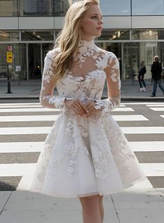 a woman in a white dress is standing on the street