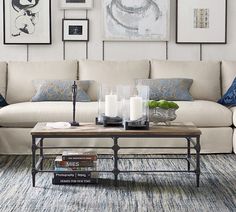 a living room with white couches and blue pillows on the floor next to a coffee table