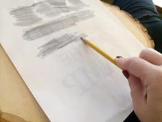 a person is holding a pencil and drawing on paper