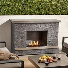 an outdoor fireplace is shown with fruit and wine on the coffee table next to it