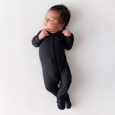 a baby laying on its back wearing a black onesie