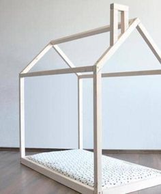 a dollhouse bed made out of wood and white paint on top of a hard wood floor