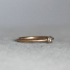 "Modern diamond pebble wedding ring. A sparkly 2.5mm sparkly white diamond is set in a handmade pebble. Wear it alone for an elegant wedding ring, or stack them up for a sparkly statement. Details: *Finish - Comes with a brushed satin finish (pictured) unless you contact me to request a high polish. *Diamond - 2.5mm, conflict-free **Available in 14k rose gold for the same price as 14k yellow gold....If you want rose gold, purchase the 14k yellow and leave me a note in the \"note to seller\" sect Diamond White Stackable Rings With Single Diamond For Gifts, Delicate Diamond White Stackable Rings With Single Diamond, Stackable Diamond Rings With Single Diamond For Gift, Diamond Stackable Rings With Single Diamond For Gift, Promise Stackable Rings With Single Diamond In Diamond White, Gift Stackable Diamond Rings With Single Diamond, Minimalist White Topaz Ring With Single Diamond, Wedding Stackable Diamond Rings With Single Diamond, White Topaz Diamond Ring For Gift