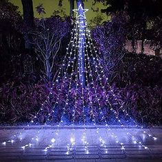 a lighted christmas tree in the middle of a garden