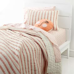 a bed with pink and white striped bedspread, pillows and pillowcases