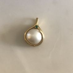 This is a gorgeous Mabé Pearl Pendant surrounded by a 14K gold setting. A beautiful vibrant green Emerald perches on top of the elegant bale. Bale can fit up to a 3mm chain. This is a nice weighty pendant at 4.38 grams. Mabé pearls, also known as blister pearls ,are half-pearls that are cultivated on the inside of a mollusk's shell. A small nucleus, usually made out of mother of pearl, is attached to the shell of the mollusk and left to accumulate nacre over a period that usually runs about two Elegant Green Gemstones In 14k Gold, Exquisite Yellow Gold Round Gemstones, Elegant Gemstones With Bezel Setting For Formal Occasions, Luxury Formal Birthstone Gemstones, Elegant Formal Gemstones With Bezel Setting, Elegant Bezel Set Gemstones For Formal Occasions, Elegant Round Gemstones For Anniversary, Elegant Round Cut Emerald Gemstones, Elegant Emerald Pendant Gemstones