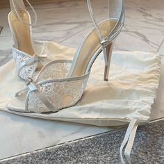 a pair of white high heeled shoes sitting on top of a piece of cloth