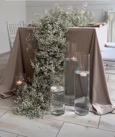 two tall vases with flowers and candles are on the floor next to each other