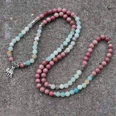 Amazonite Is A Soothing Stone. Wear It And You Will Immediately Feel A Sense Of Inner Peace And Balance. It Possesses A Powerful Energy, Like The River Of Which It Bears The Name, But It Is Nevertheless Capable Of Taming And Calming Negativity And Anger. Rhodonite Helps To Balance The Emotions And Calm Impatience. Rhodonite Is A Very Supportive Stone That Works With The Heart Chakra To Attract Love And Ground Negative Energies. Physically, Rhodonite Is Believed To Support Detoxification And Heal Spiritual Pink Beaded Crystal Necklaces, Handmade Pink Spiritual Beaded Necklace, Handmade Spiritual Pink Beaded Necklaces, Bohemian Pink Crystal Necklace With Gemstone Beads, Pink Bohemian Crystal Necklace With Gemstone Beads, Spiritual Pink Beaded Necklaces For Jewelry Making, Bohemian Pink Gemstone Bead Necklaces, Pink Round Beads Crystal Necklaces For Jewelry Making, Spiritual Pink Beaded Necklaces With Natural Stones