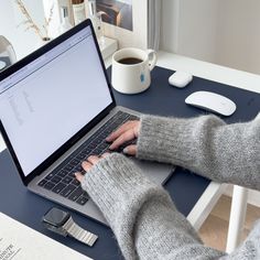 a person sitting at a table using a laptop computer with their hands on the keyboard