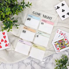 game night cards laid out on top of a table with plants and playing cards next to them