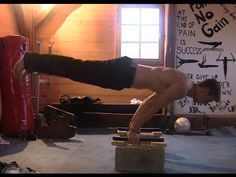 a shirtless man doing a handstand in a room with boxing gloves on the floor