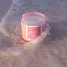 a pink candle sitting on top of a sandy beach