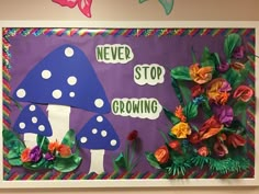 a bulletin board with paper flowers and a mushroom on the bottom, says never stop growing