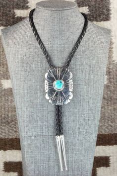 This turquoise and sterling silver bolo tie was made by Navajo silversmith Rosita Singer. The back is signed T&R Singer and stamped sterling.Tie Length: 22"Length: 2 3/8"Width: 1 3/4"Tips:Length: 2 1/8"Width: 1/4"Free shipping on all orders! We ship with USPS and always include tracking. All orders ship within a day of payment.Returns are accepted up to 30 days after you receive your order. Just send us a message. Our shop offers cash back or store credit. The item must be returned in new condit Handmade Lariat Bolo Tie For Rodeo, Blue Lariat Bolo Tie For Gift, Western Style Engraved Jewelry For Rodeo, Western Engraved Jewelry For Rodeo, Southwestern Lariat Turquoise Necklace, Southwestern Adjustable Lariat Turquoise Necklace, Southwestern Adjustable Turquoise Lariat Necklace, Adjustable Southwestern Turquoise Lariat Necklace, Southwestern Jewelry With Sliding Knot As A Gift