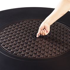 a person is touching the center of a round table top with their hand on it