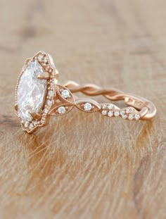 an engagement ring with a pear shaped diamond in the center on top of a wooden surface