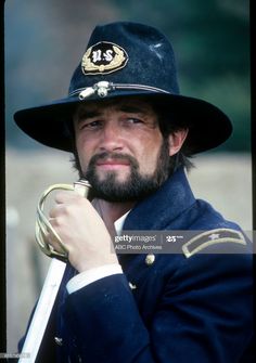 a man with a beard wearing a hat and holding a cane in his hand stock photo