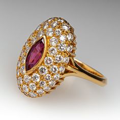 This elegant ring is centered with one (1), bezel set, marquise mixed cut natural ruby. The ruby is bordered with fifty-two (52), bead set, round brilliant cut diamonds. The ring has a reverse tapered "knife edge" style shank. The ring measures 19.5mm at the top, rises 7.7mm above the finger, tapering to 2.7mm wide and 1.6mm thick at the base of the shank. This ring is currently a size 6.75. The ring shows a lovely soft patina. Luxury Marquise Ruby Ring With Diamonds, Luxury Marquise Ruby Ring, Luxury Marquise Red Ruby Ring, Luxury Red Marquise Ruby Ring, Marquise Ruby And Diamond Multi-stone Ring, Luxury Marquise Cut Red Ruby Ring, Marquise Ruby Ring With Diamonds, Luxury Red Marquise Cut Ruby Ring, Marquise Multi-stone Ruby Ring In Fine Jewelry Style