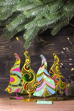 three colorful christmas trees sitting on top of a wooden table