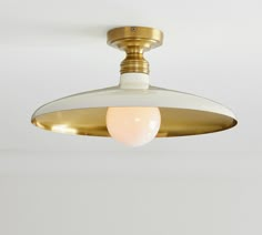 a white and gold ceiling light hanging from the ceiling in a room with no one around it