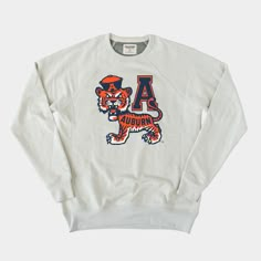 This classic college logo was designed by Art Evans for Angelus-Pacific, one of the first companies to design college mascots (founded back in 1932). You've probably seen a few variations of a tiger wearing a sailor hat, but we're partial to this Auburn version printed on our super soft crewneck. Products are mocked up on a size S. Graphics may appear smaller on larger sizes. High School Apparel, Cute College Merch, Auburn Outfits, Lazy Fits For School, Adpi Recruitment, College Sweatshirt Outfit, Auburn Clothes, Auburn Sweatshirt, Ut Game