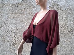 Sheer silk mousseline chiffon 100% crop jacket with balloon sleeve in burgundy and white color. This silk transparent crop jacket is a stylish and versatile piece that adds a touch of elegance to any outfit. The transparent design allows for a subtle peek at the clothing underneath, while the cropped length and flowing silk fabric provide a flattering and feminine silhouette. The 3/4 sleeves add a luxurious touch and make this bolero shrug perfect for pairing with evening dresses or formal attir Elegant Fitted V-neck Shrug, Elegant Sheer Sleeves Crop Top For Spring, Elegant Crop Top With Sheer Sleeves For Night Out, Elegant Spring Crop Top With Sheer Sleeves, Elegant Party Shrug For Fall, Elegant Fall Party Shrug, Elegant Crop Top With Blouson Sleeves, Elegant Cropped Spring Shrug, Elegant Cropped Shrug For Spring