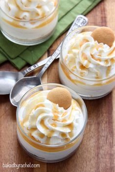 two desserts with whipped cream and caramel on top, sitting on a wooden table