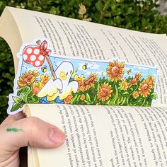 a person holding an open book in their hand with a cartoon sticker on it