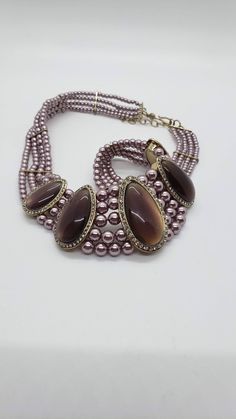 This is a beautiful piece of jewelry from Monet, featuring five teardrop shaped cabochons surrounded by crystal rhinestones, suspended on four strands of graduated faux pearls. The choker necklace measures 16 1/2 inches long by 1 3/8 inches at the widest point. There is a 2 inch extension chain. The cabochons have a smoky brown color that changes to a light amethyst or lavender. The same can be said of the faux pearls, which look more lavender than brown, depending on the light. The four strands Lavender Brown, 1928 Jewelry, Light Amethyst, Vintage Monet, Leaf Necklace, Choker Necklaces, Gold Pearl, Vintage Jewellery, A Hook