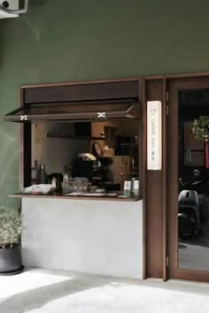 the outside of a restaurant with potted plants in front of it and an open door