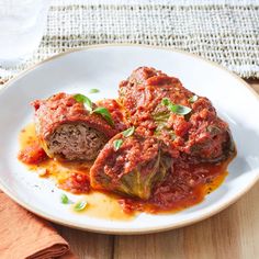 two stuffed cabbages on a plate with sauce