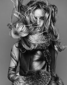 a woman with long hair and tattoos on her arm is posing for a photo in black and white