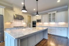 a large kitchen with an island in the middle and two pendant lights hanging from the ceiling