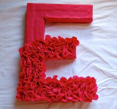 the letter e is made out of red yarn and has ruffles on it