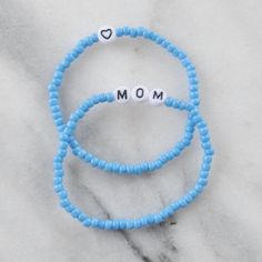 Looking for the perfect gift for your mom this Mother's Day? Look no further than our MOM stretch bracelet set in vibrant, playful colors! It's a fun and unique way to show your appreciation to the most important woman in your life. SOLD IN A SET OF 2: one says "MOM", one has a heart 2-3mm chunky glass beads with flat white letter beads available in 6.5" one-size-fits-most (custom sizing not available at this time) strung on stretch cords for easy on and off style comes in 3 fun colors: choose Sky, Sunshine, or Bubblegum packaged in a clear resealing bag for storage and gift giving to keep your jewelry looking new, avoid water, lotions and perfumes Mother's Day Stretch Bracelet With Letter Beads, Playful Beaded Jewelry For Mother's Day, Casual Stackable Stretch Bracelet Gift, Casual Stackable Stretch Bracelet As Gift, Blue Friendship Bracelets For Mother's Day Gift, Casual Letter Beads Stretch Bracelet For Mother's Day, Trendy Beaded Bracelets For Mother's Day, Fun Blue Bracelets For Gifts, Blue Name Bracelet For Mother's Day Gift