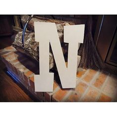 the letter n is made out of wood and sits on top of a brick bench