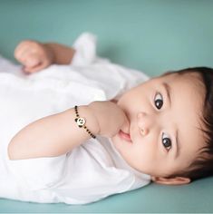 a baby laying on its back wearing a bracelet