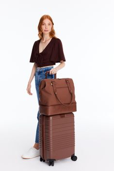 a woman standing next to a brown suitcase