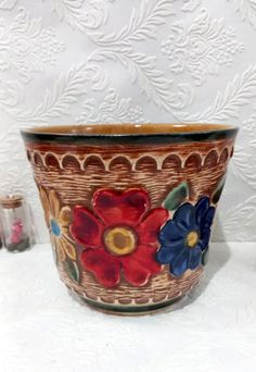 a large flower pot sitting on top of a white table next to thread spools