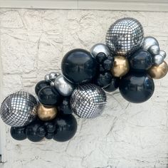 a bunch of black and gold balloons hanging from the side of a building