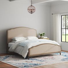 a bedroom with a bed, rug and chandelier hanging from the ceiling in front of a window