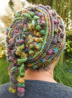 a woman wearing a multicolored crocheted headband with braids on her hair