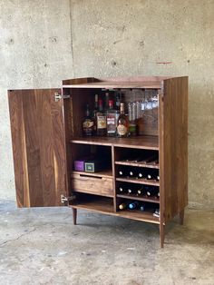 a wooden cabinet with wine bottles and glasses on it's doors, in front of a concrete wall