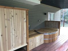 a wooden bench sitting on top of a wooden deck next to a barrel filled with water