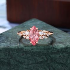 a pink diamond ring sitting on top of a green marble slab