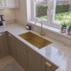 a kitchen with marble counter tops and gold faucet sink in front of a window